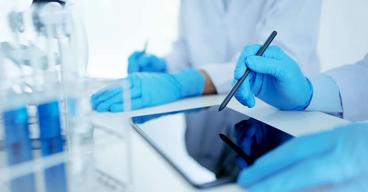 Lab techs working at a desk with tablet devices
