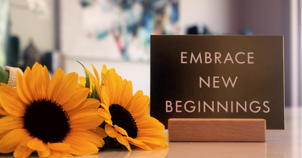 sunflowers on counter with sign reading embrace new beginnings