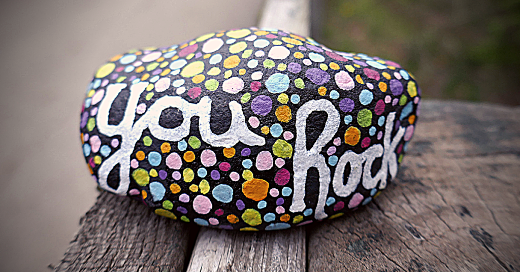 rock painted with polka dots and you rock saying sitting on wooden bench