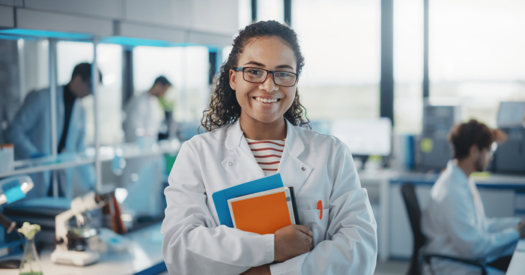 student in lab wearing white coat with text books during their life sciences internships